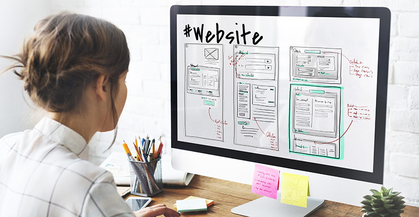 Woman sitting at desktop computer working on website design layout