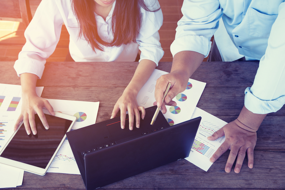 Two co-workers review documents on a computer